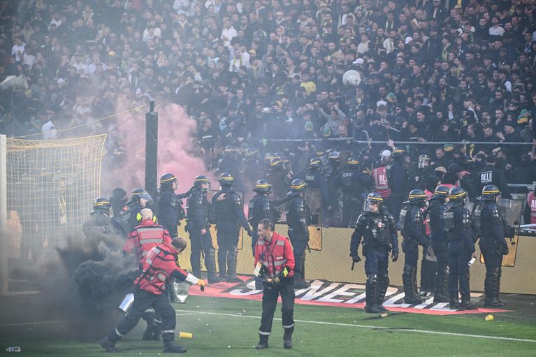 Les supporters nantais quittent la pelouse sous bonne garde, entourés par les forces de l'ordre