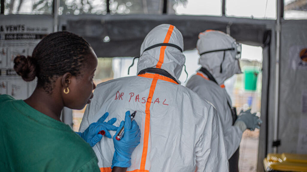 Un agent d'hygiène inscrit le nom d'un médecin au dos de sa combinaison de protection individuelle avant d'entrer dans un centre de traitement Ebola situé à Bunia (Ituri), dans l'est de la République démocratique du Congo.