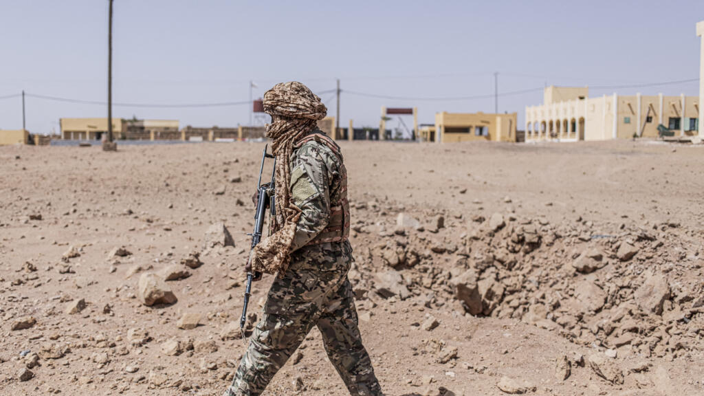 Un soldat inspectant un cratère causé par un bombardement aérien à Kidal, mettant en lumière la menace jihadiste dans la région