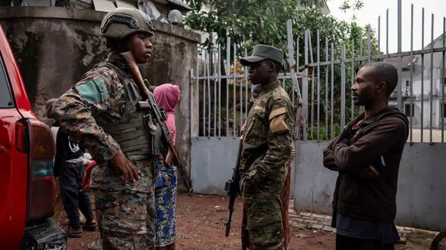 Deux militaires en uniforme et un civil discutant près d'une zone de conflit en République démocratique du Congo